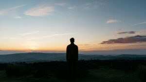 Silhouette einer stehenden Person vor einer tiefstehenden goldenen Sonne